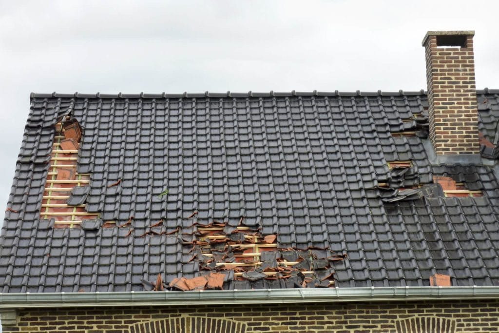Toiture endommagée avant intervention, tuiles arrachées sur plusieurs rangs