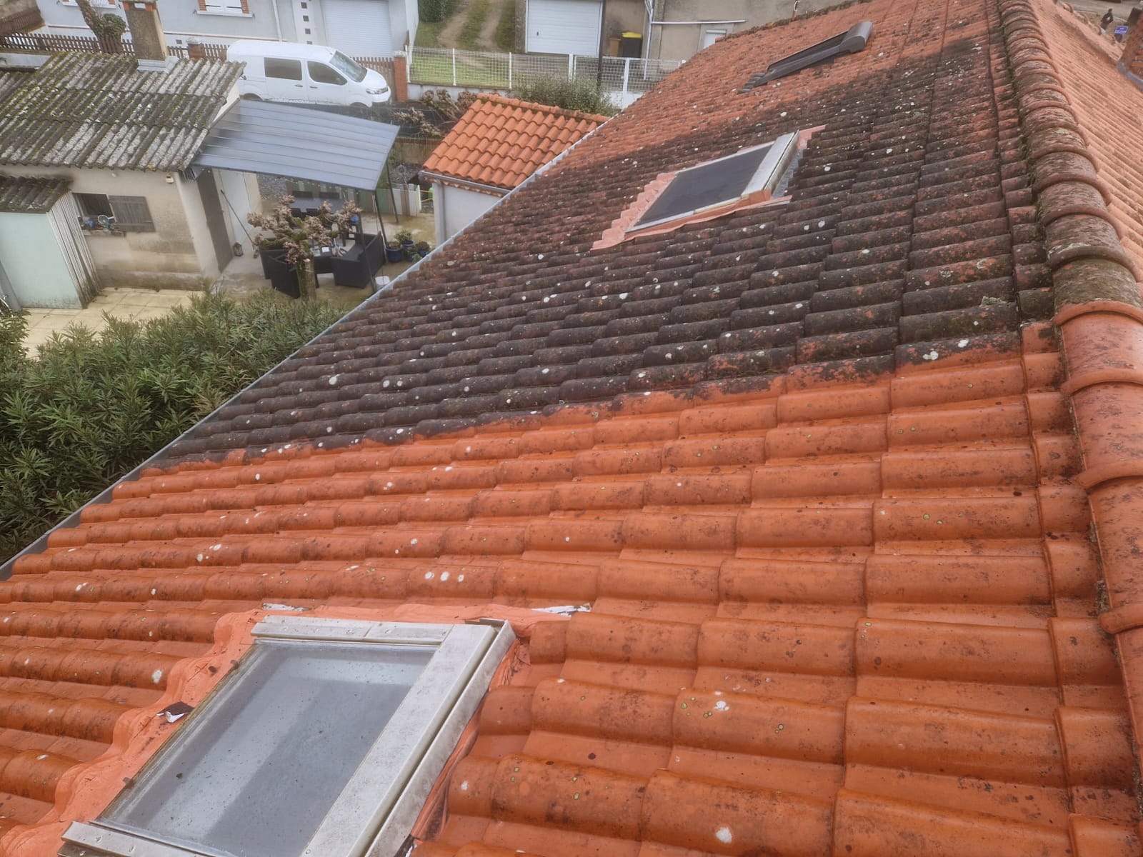 Démoussage de toiture en cours, moitié traitée et moitié encore encrassée