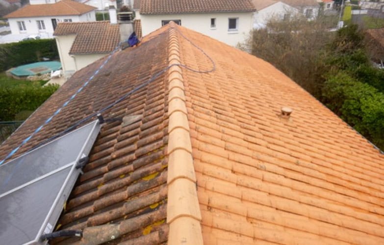 Démoussage de toiture en cours sur une maison de bastide à Briatexte